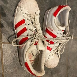 Adidas Superstars with hearts and shiny red stripes.